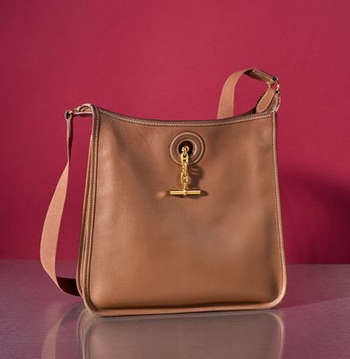 beige leather purse with gold metal hardware on a shiny surface