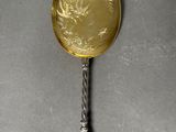 silver spoon with a gold coin on it sitting on a gray surface