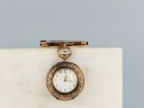 a close up of a small gold pocket watch on a marble block