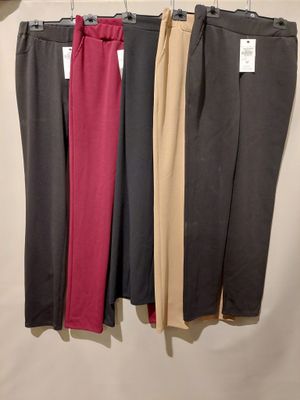 trois paires de pantalons pour femmes suspendues à un portant devant un mur blanc