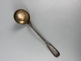 an antique spoon with a long handle on a white surface