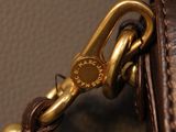 brown leather purse with a gold clasp on a brown background