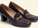 La femme porte une paire de chaussures marron ornées d'une chaîne dorée au talon.