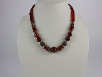 a close up of a necklace with red beads on a mannequin