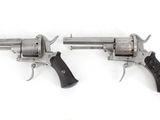 two revolvers are shown on a white surface with a white background