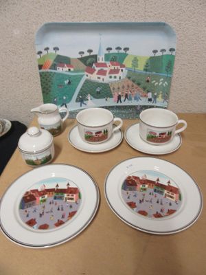 quatre assiettes et tasses posées sur une table, avec en arrière-plan une photo d'une ville