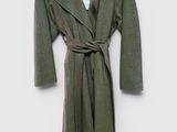 un manteau vert suspendu à un cintre accroché au mur, sur fond blanc