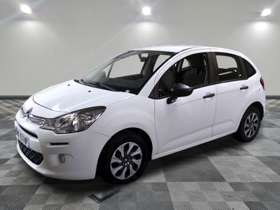 the small white car is parked on a checkered floor