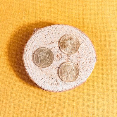 a small white plate with coins on it on a yellow surface