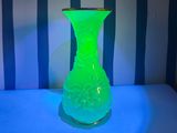 a green vase sitting on a table in front of a striped wall