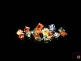 un gros plan sur un assortiment de diamants de différentes couleurs posés sur une surface noire