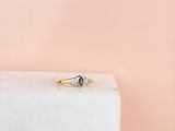 Une bague en or sertie d'un saphir bleu repose sur un bloc de marbre