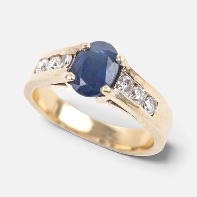 a close up of a gold ring with a sapphire and diamonds