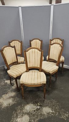 six chaises et une table dans une pièce aux murs gris