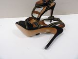 black and gold high heeled sandals with straps on a white surface