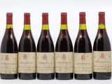 six bouteilles de vin sont alignées sur une surface blanche