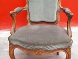 an old chair with a blue upholstered seat in front of a red wall