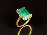 un gros plan d'une bague avec une pierre verte sur un fond noir