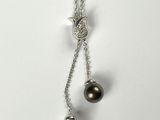 a close up of a necklace with two pearls on a chain