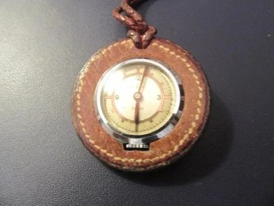 une petite montre de poche avec un bracelet en cuir, posée sur une table