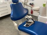 un fauteuil bleu dans le cabinet du dentiste, avec une télévision accrochée au mur