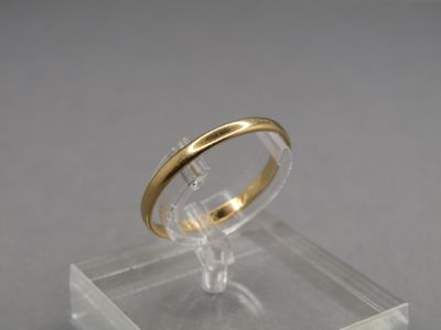 a gold ring on a clear stand on a gray surface