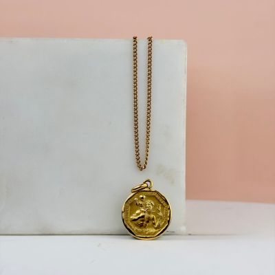 un collier en or avec une pièce d'or posée sur un bloc de marbre blanc