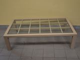 une table basse avec un plateau en verre posée sur un sol carrelé