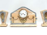 une horloge et deux vases posés sur une surface blanche