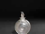 une petite bouteille en verre surmontée d'un oiseau