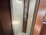 a shower in the corner of a bathroom with a skylight above it