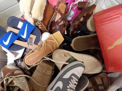 many pairs of shoes and bags in a pile