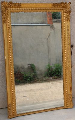 a mirror sitting on the ground next to a vase