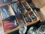 a drawer full of utensils and glasses on a table