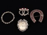 three silver brooches with red and white stones on a black background