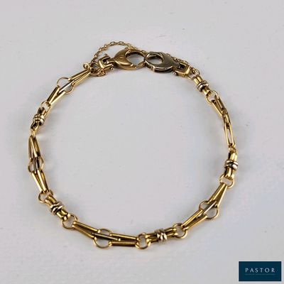 gros plan d'un bracelet en or sur une surface blanche