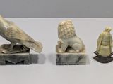 three carved figurines of a bird, lion, and a man