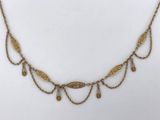 a gold necklace with a leaf design on a chain