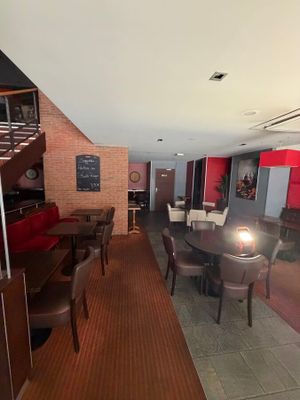 tables and chairs in a room with a staircase leading up to the second floor