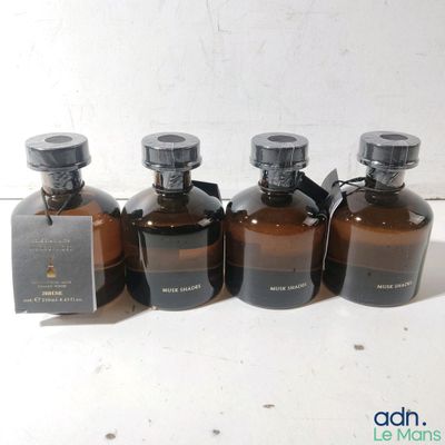 quatre flacons de parfum sont alignés sur une surface blanche