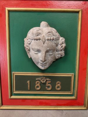 a picture of a plaque of a woman ' s face on a green and red frame