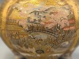 a gold vase with a painting on it sitting on a table