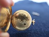 a close up of a person holding a gold pocket watch