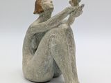 sculpture of a woman sitting on her knees with a bird in her hand