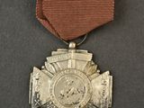 an old medal with a ribbon around it on a black surface