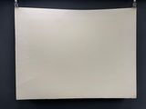 une feuille blanche accrochée à un mur noir dans une pièce sombre