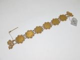 a close up of a gold bracelet on a white surface