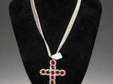 a close up of a necklace with a cross on a mannequin