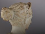 marble bust of a woman with long hair and a bun on her head