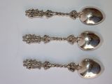 three silver spoons sitting on top of a white table